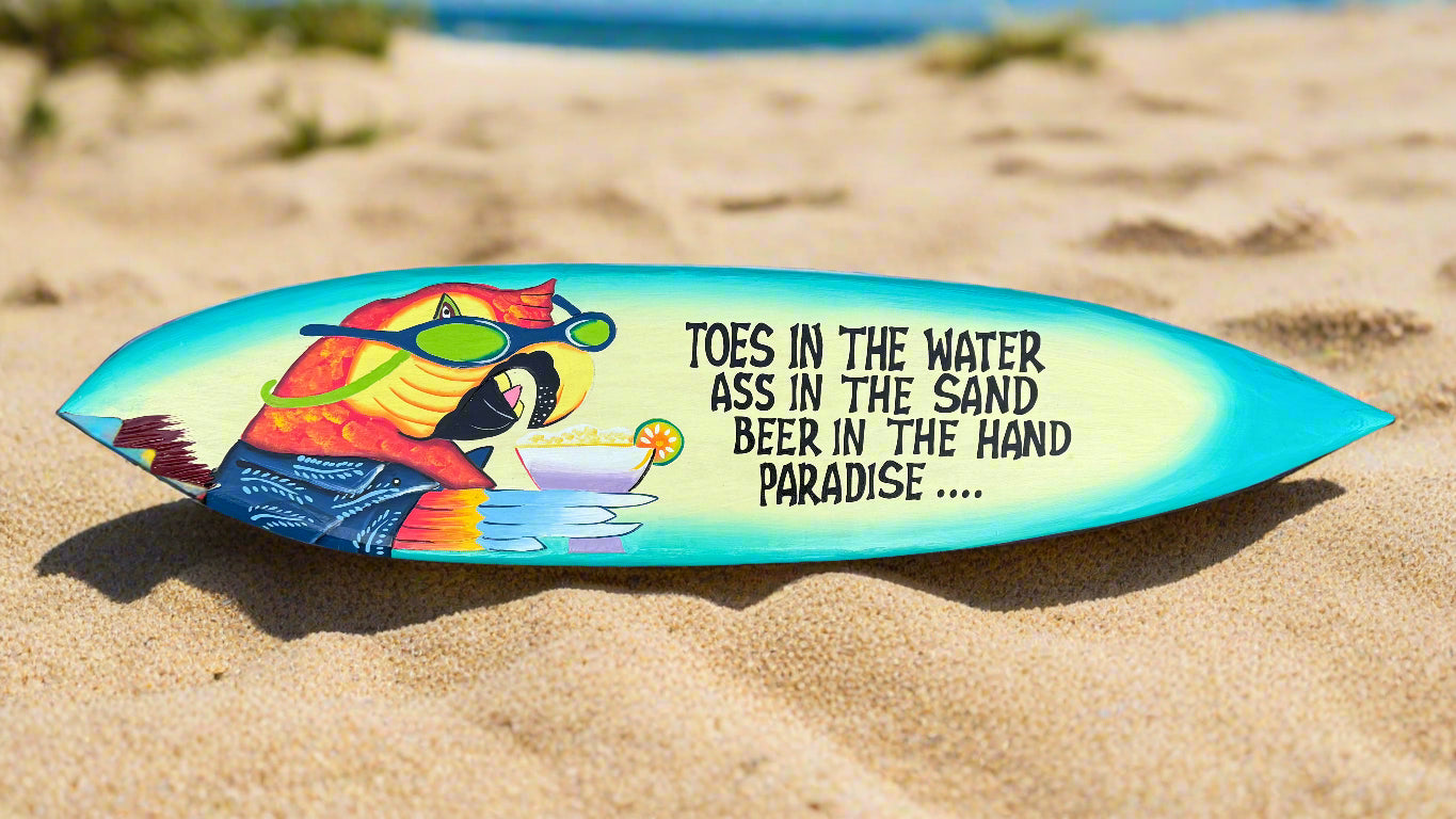 Colorful surfboard with parrot illustration and beach quote on sandy beach