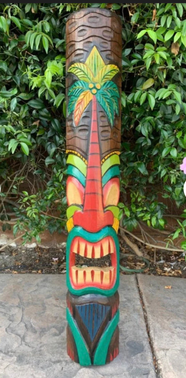 Colorful tiki carved pole with a palm tree design in a garden setting