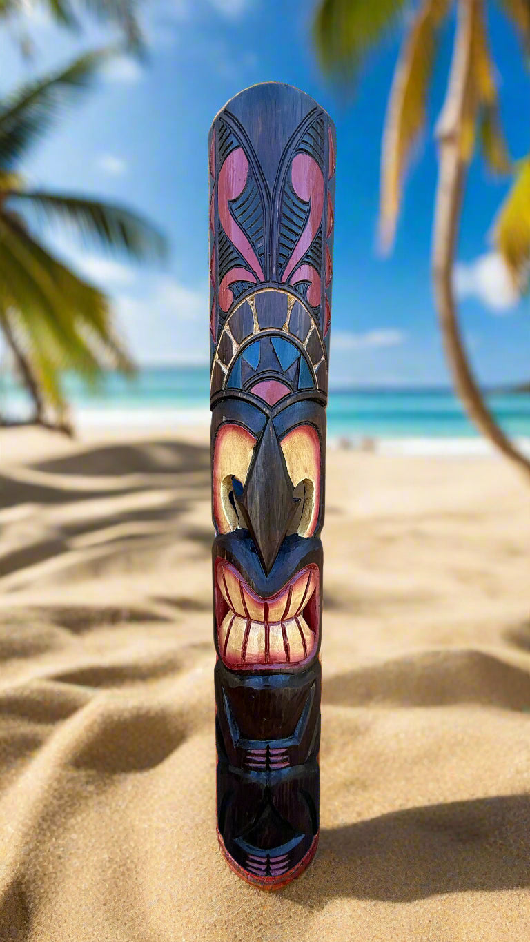 Colorful carved tiki totem standing on sandy beach with palm trees and blue ocean