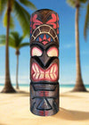 Colorful tiki totem carved from wood on a sandy beach with palm trees in the background