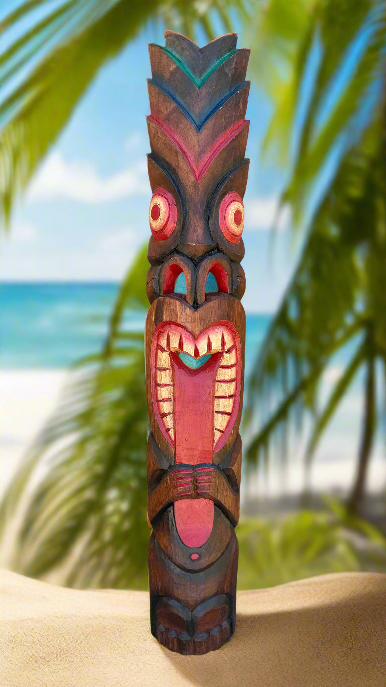 Colorful carved tiki totem pole on a sandy beach with palm trees in the background