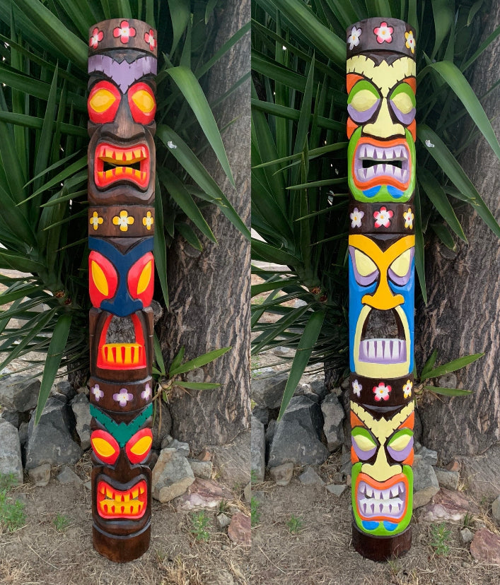 Pair of colorful tiki totem poles with floral motifs outdoors