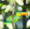 Colorful toucan perched on a twig with a large multicolored beak against a blurred green background.