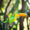 Colorful wooden toucan sculpture hanging from a vine in a garden