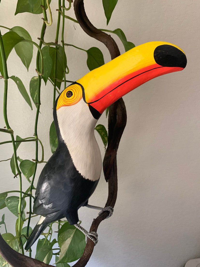 Colorful toucan sculpture perched on a branch among green vines