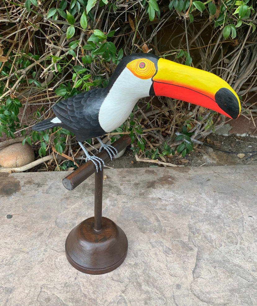 Colorful toucan sculpture perched on a metal stand outdoors