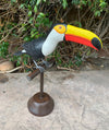 Colorful toucan sculpture perched on a metal stand outdoors