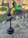Colorful toucan sculpture perched on a black stand outdoors