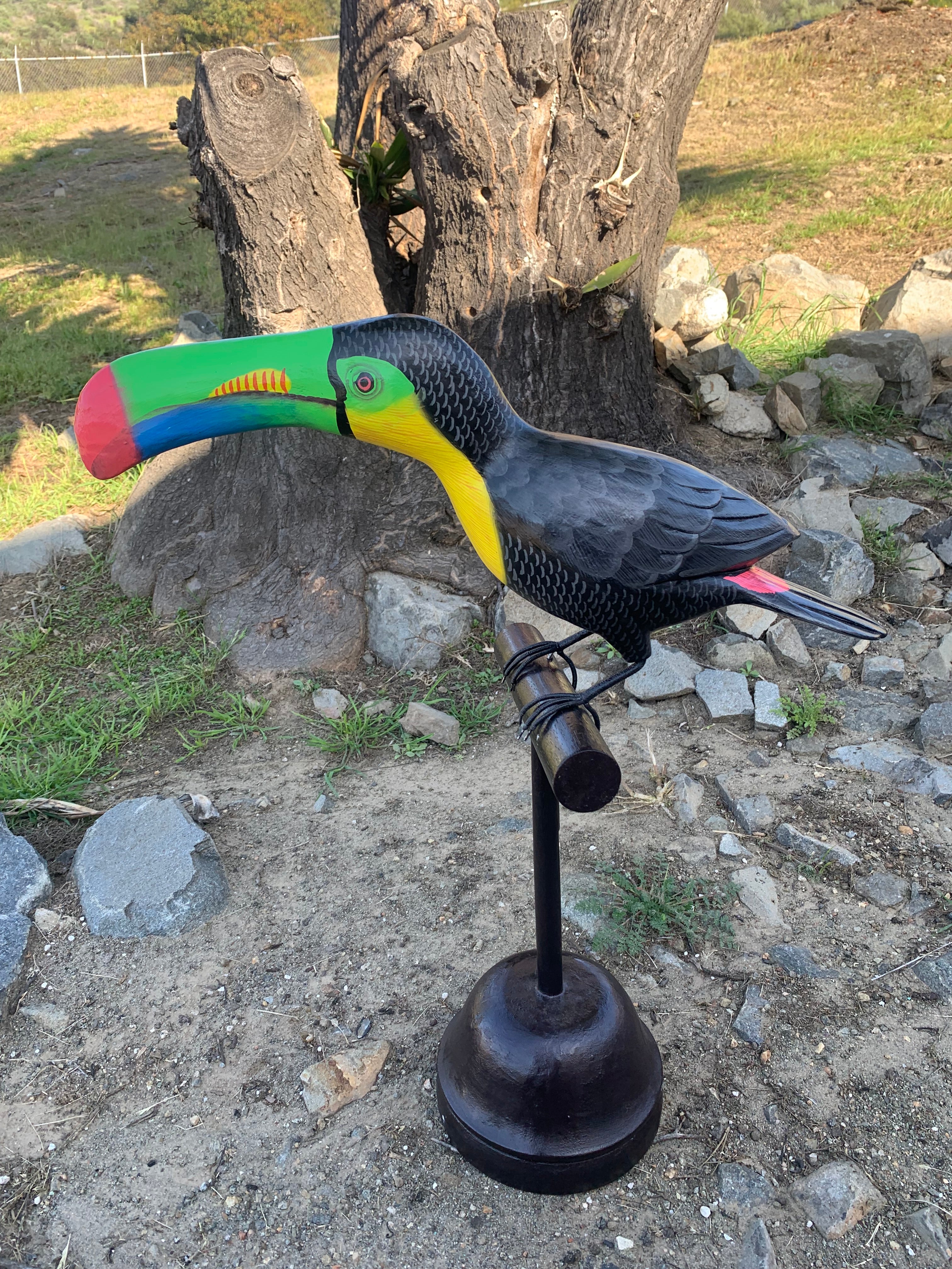 Colorful toucan sculpture on a metal stand outdoors