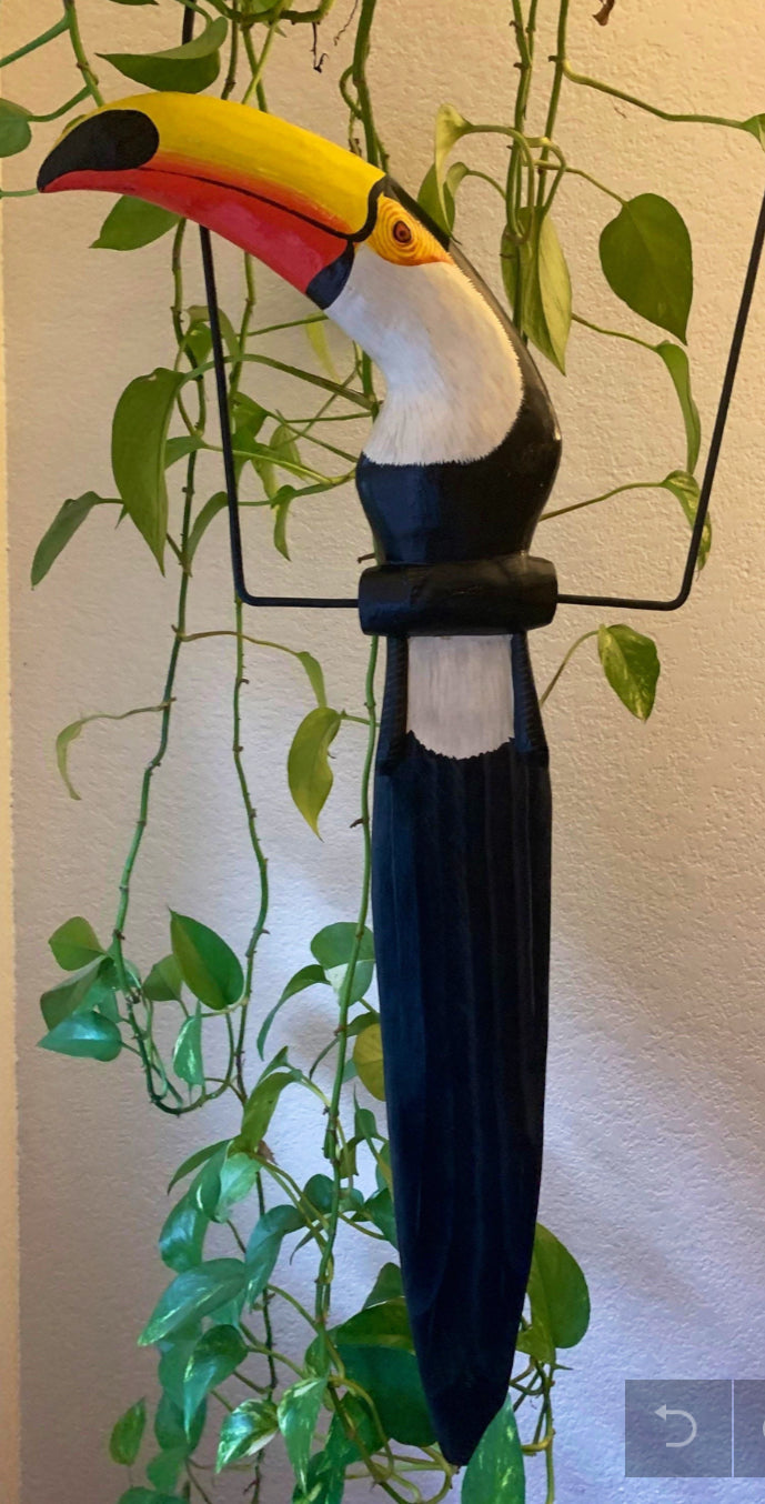 colorful toucan statue with bright yellow beak indoors among green plants