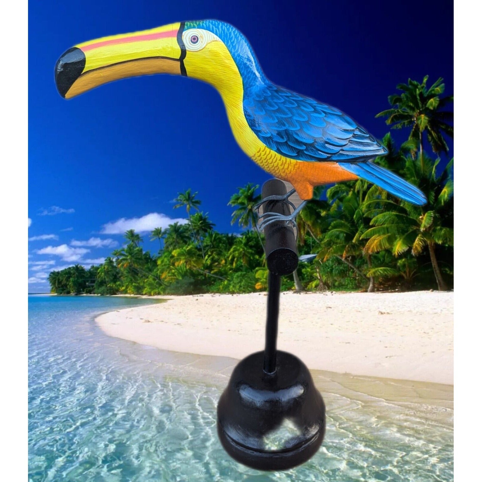 Colorful toucan statue perched on a stand at a tropical beach with palm trees