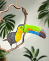 Brightly colored wooden toucan sculpture perched on a twisting branch.