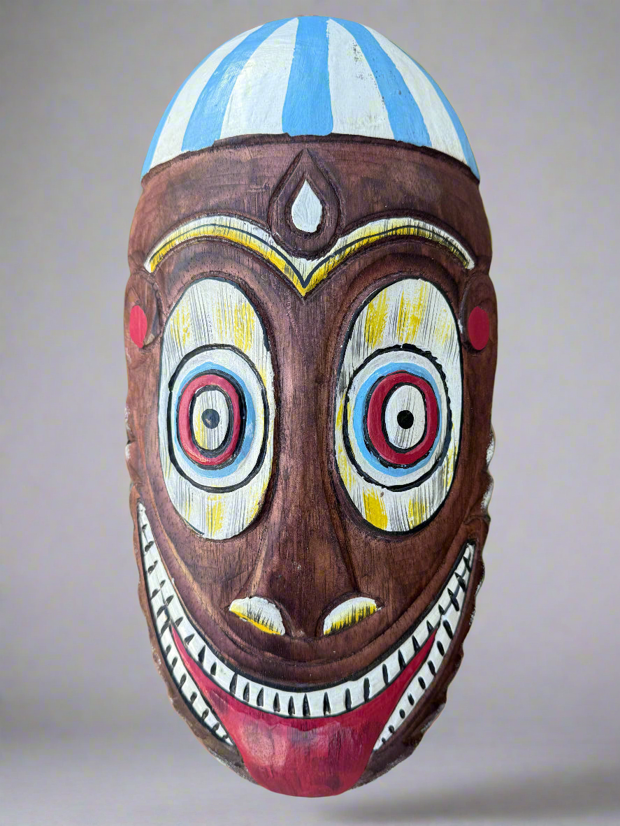Colorful carved wooden mask with wide circular eyes and broad smile.