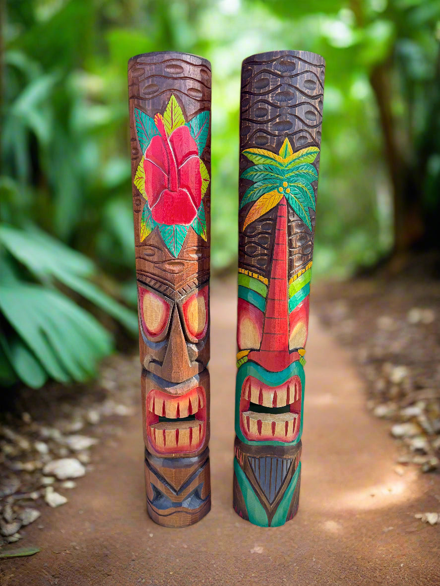 two colorful wooden tiki totem poles with carved faces and tropical designs on a garden path