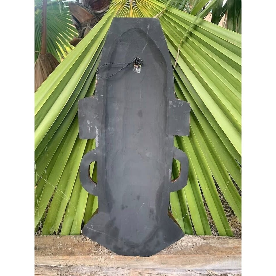Dark metal shield-shaped wall decor with side handles and hanging loop