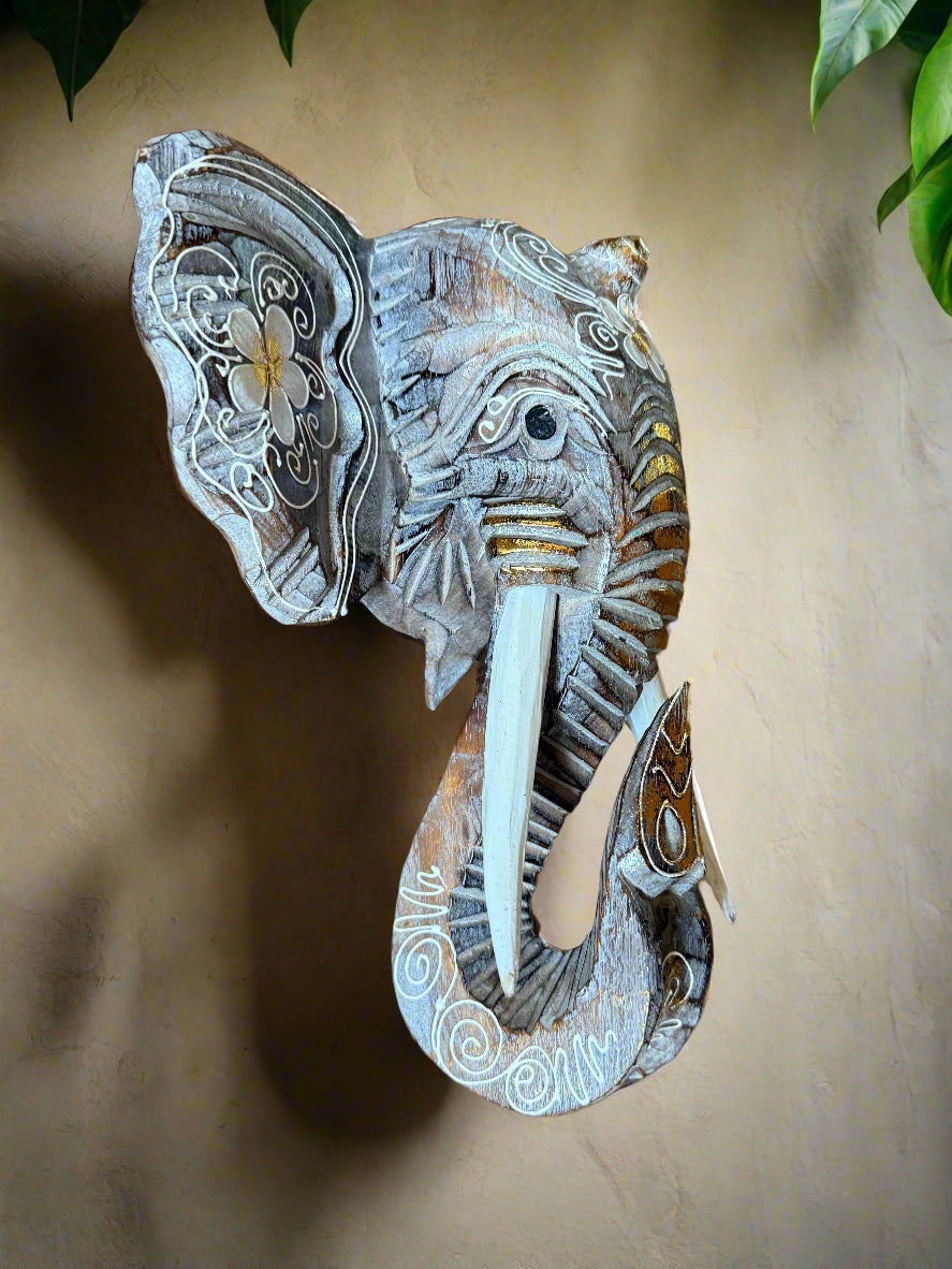 Decorative carved elephant head wall sculpture with ornate white scroll patterns and a blue-gray finish.