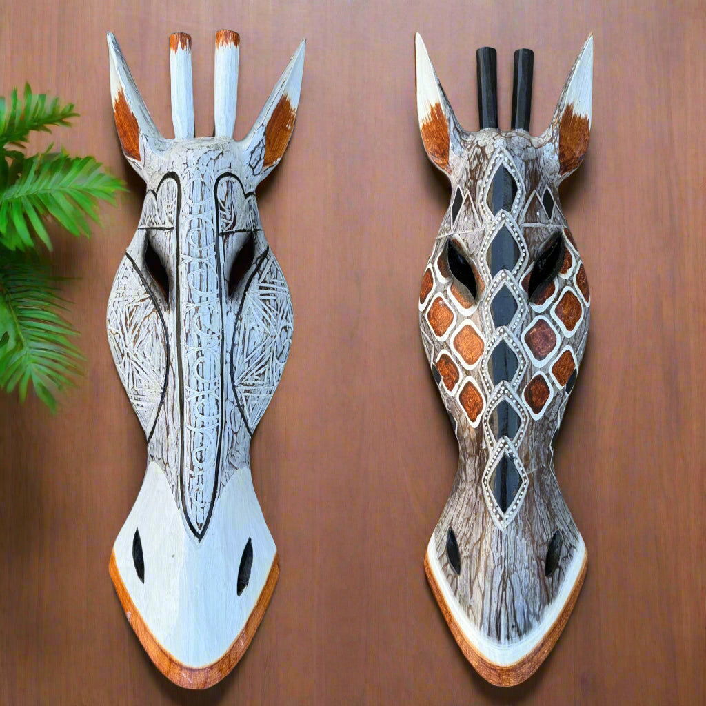 Two decorative carved wooden giraffe heads with geometric patterns mounted on a wooden wall