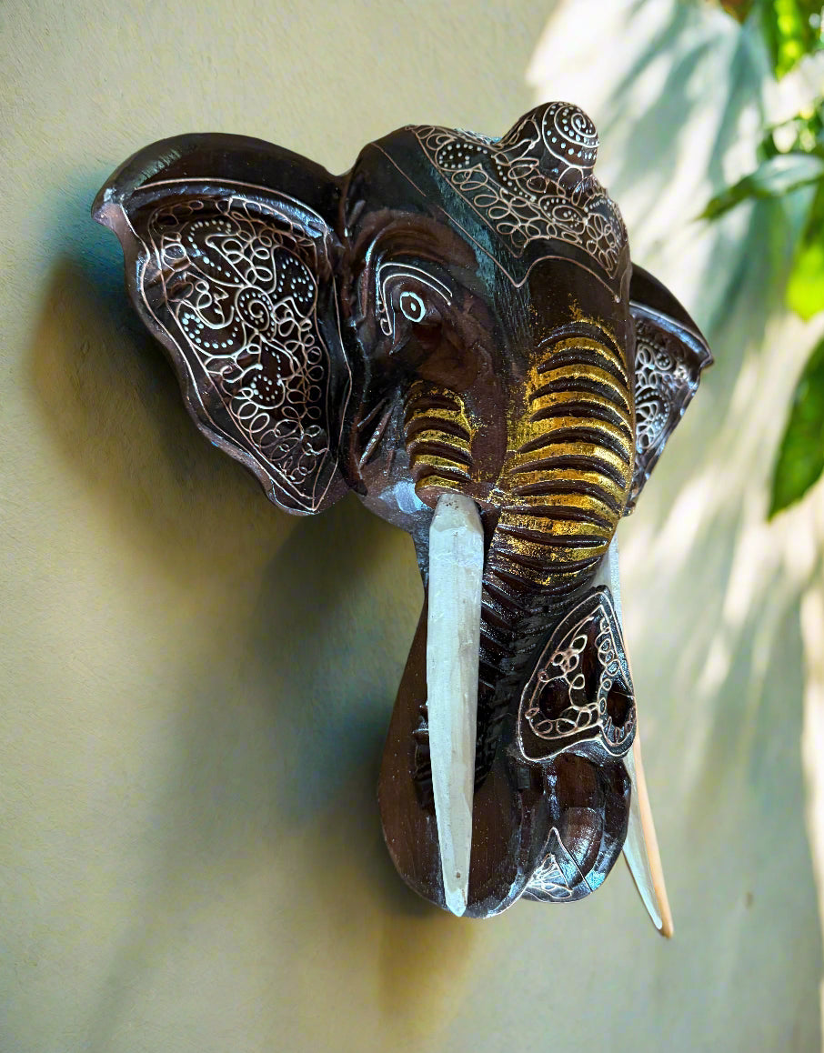 Decorative wooden elephant head wall sculpture with intricate white engravings and tusks
