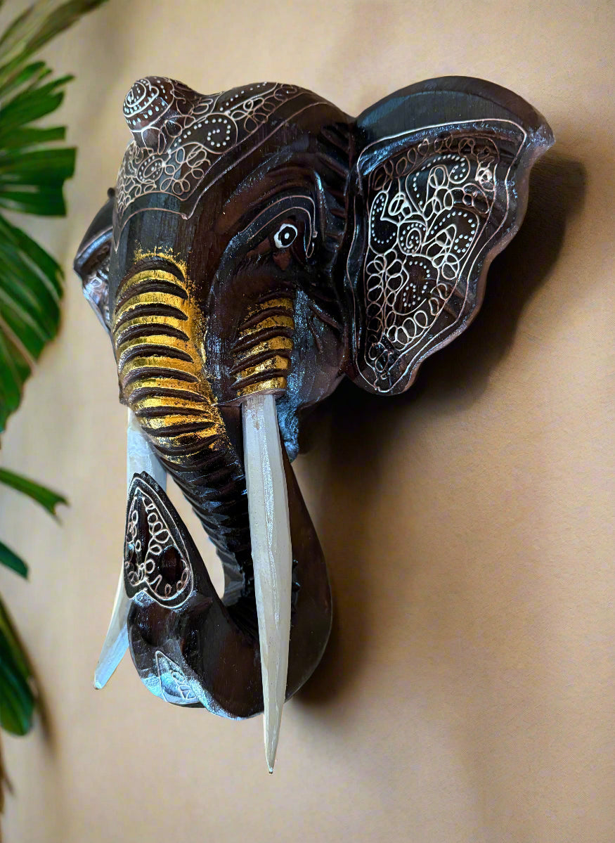 Decorative black elephant head wall sculpture featuring white-inked patterns and gold-tinted tusks.