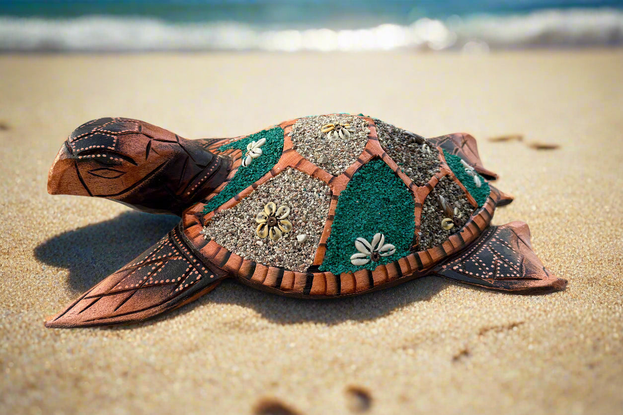 colorful mosaic sea turtle sculpture on a sandy beach with waves in the background