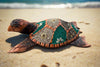 colorful mosaic sea turtle sculpture on a sandy beach with waves in the background