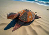 decorative mosaic sea turtle sculpture on sandy beach with ocean in background