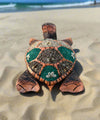 Decorative mosaic sea turtle sculpture on the sandy beach with turquoise shell panels.