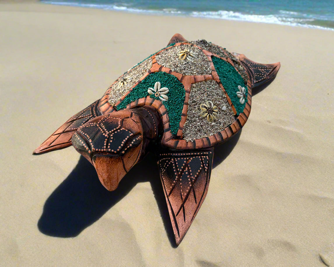 Decorative mosaic sea turtle sculpture on sandy beach by the ocean