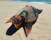 Decorative mosaic sea turtle sculpture on sandy beach by the ocean