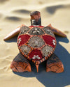 Decorative mosaic sea turtle sculpture with red and gray shell panels on sandy beach