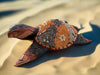 Decorative mosaic turtle sculpture with patterned shell on sandy surface