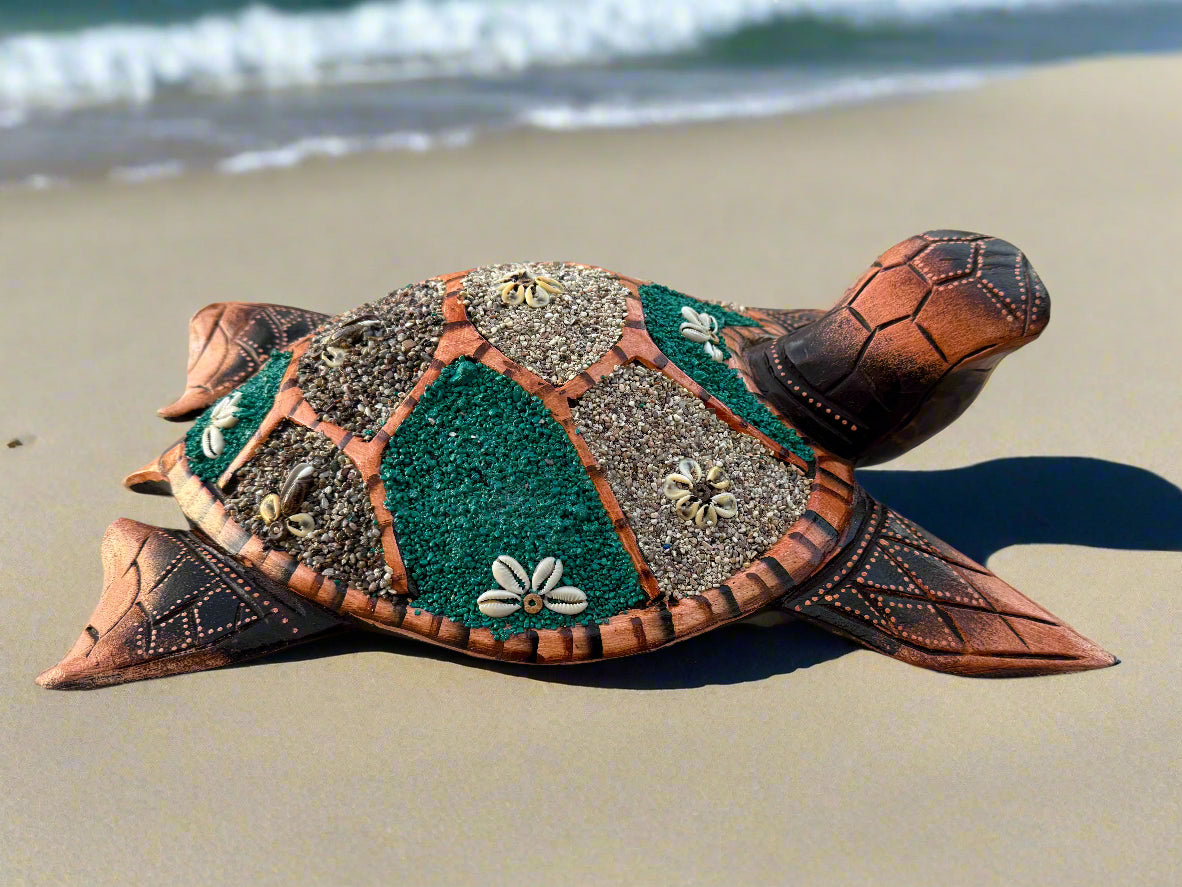 Decorative mosaic sea turtle sculpture made from shells on a sandy beach