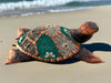 Decorative mosaic sea turtle sculpture made from shells on a sandy beach