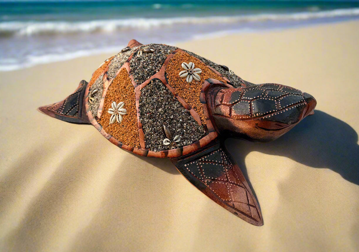 Decorative sea turtle on sandy beach with mosaic shell pattern of pebbles and shells