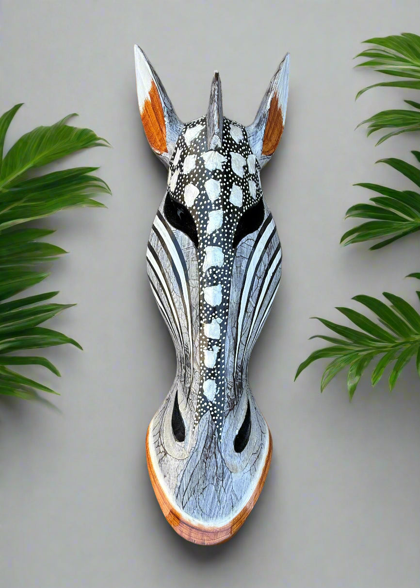 Decorative wooden horse mask with black and white spotted pattern and orange ear accents