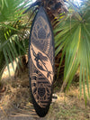 Decorative wooden surfboard featuring a mermaid and turtle motifs carved in light wood on black background