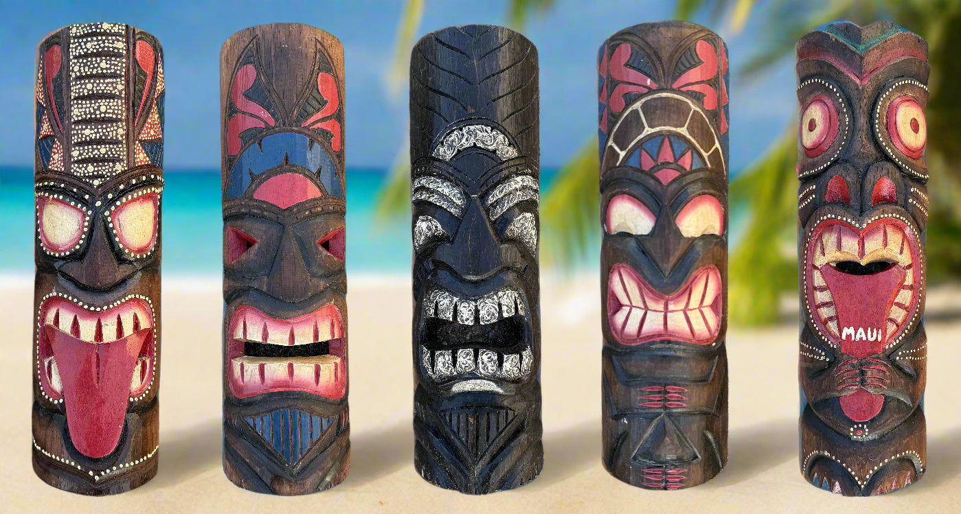 Five carved tiki totem poles on Maui beach with turquoise sea and palm trees