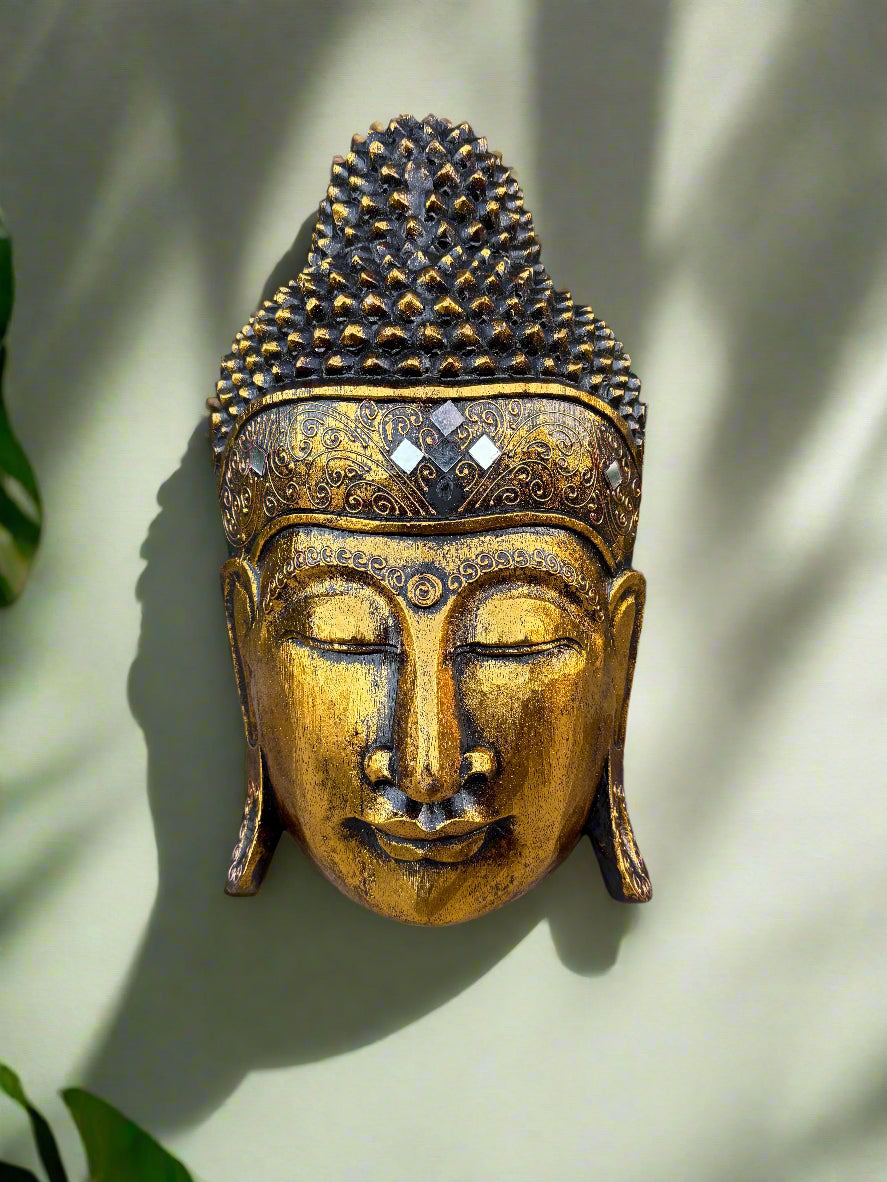 golden Buddha head statue with ornate crown and closed eyes, decorative patterns