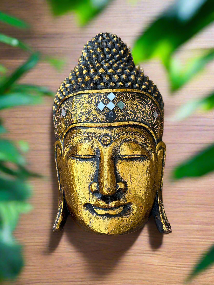 Golden Buddha head statue with ornate patterns on a wooden background