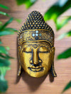 Golden Buddha head statue with ornate patterns on a wooden background