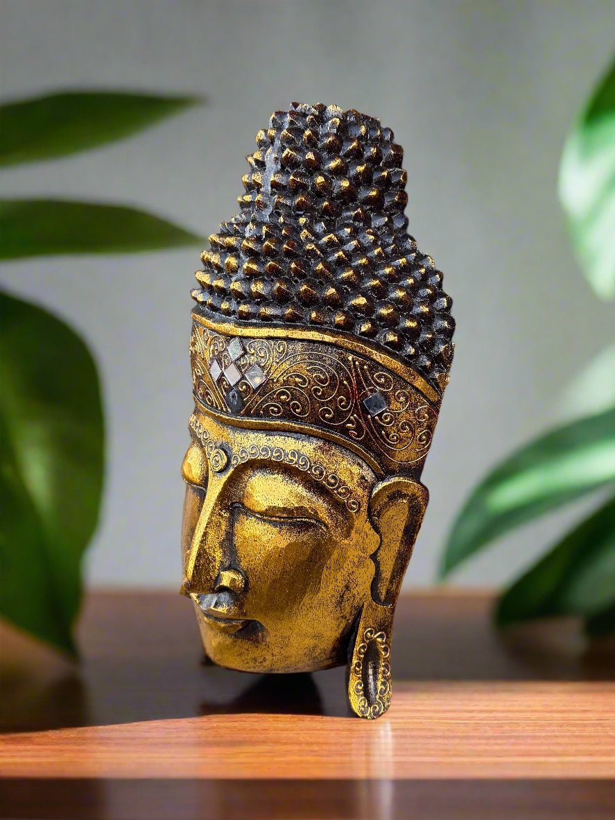 golden Buddha head statue with ornate crown on wooden table