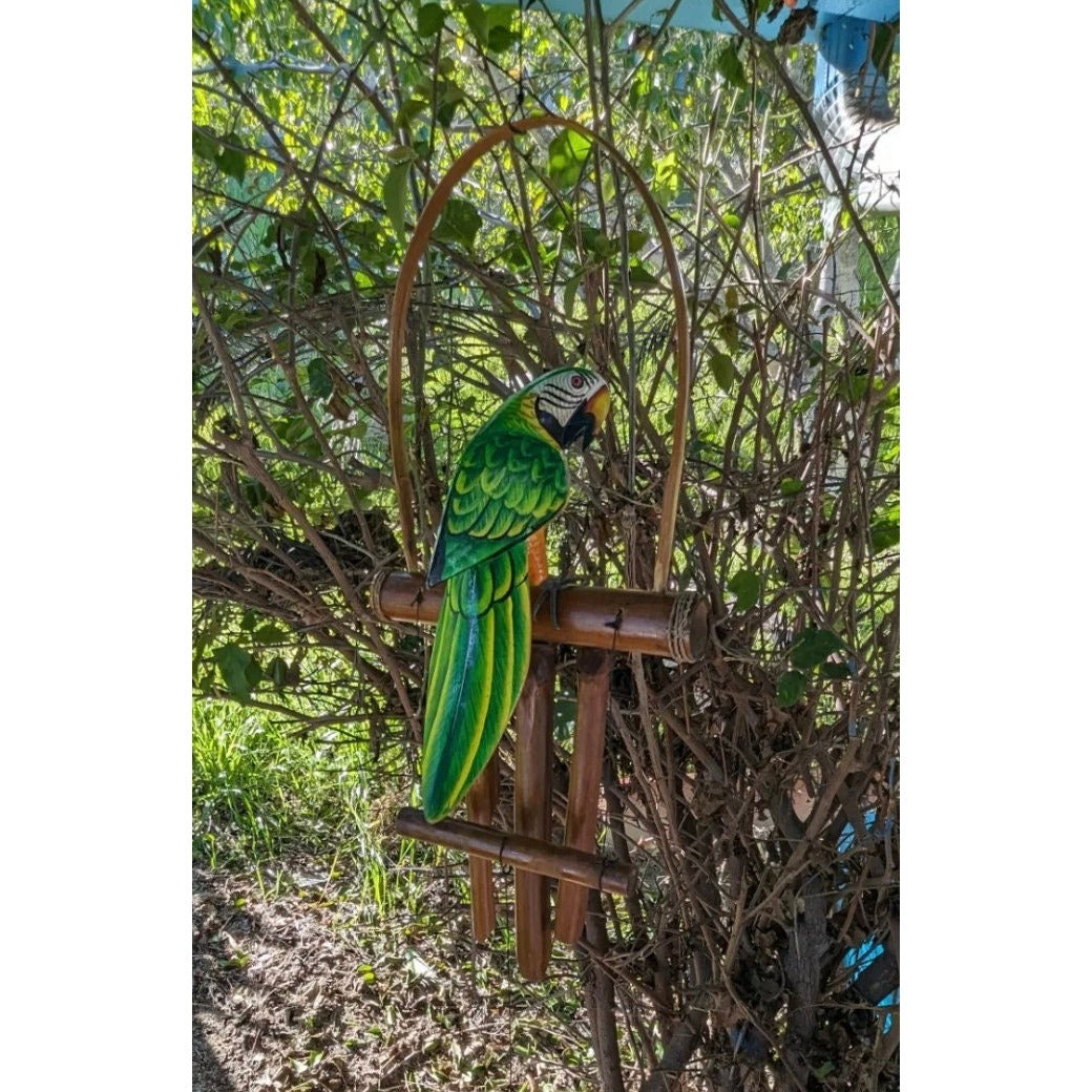 Green macaw perched on a bamboo stand in a garden