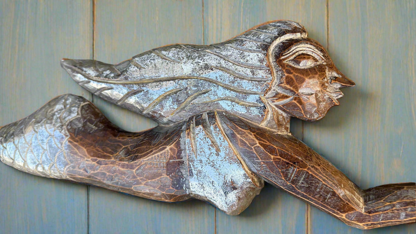 Metal sculpture of a winged humanoid figure with scale-like patterns
