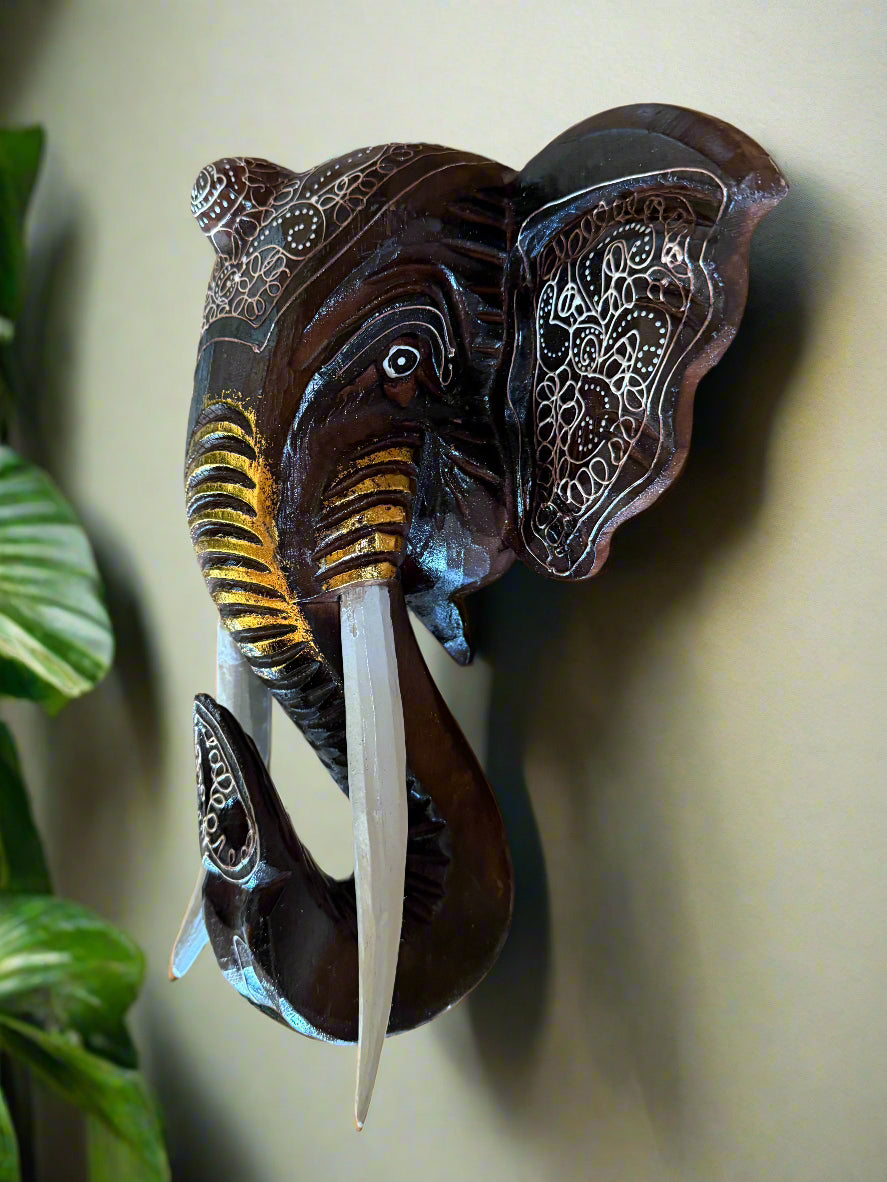 Hand-carved wooden elephant head wall sculpture with white ornate patterns and curved tusks