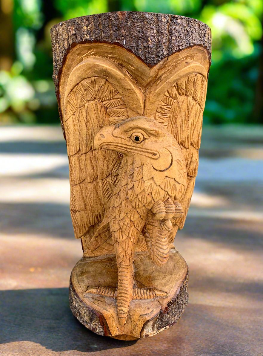 hand-carved wooden eagle perched on a log with detailed feather carving