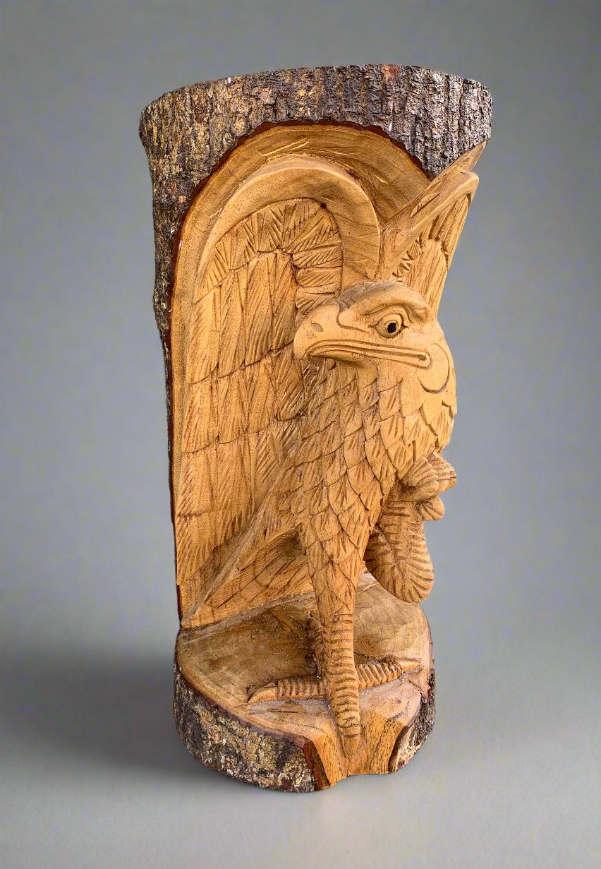Wooden eagle totem carving on birch trunk with detailed feathered wings