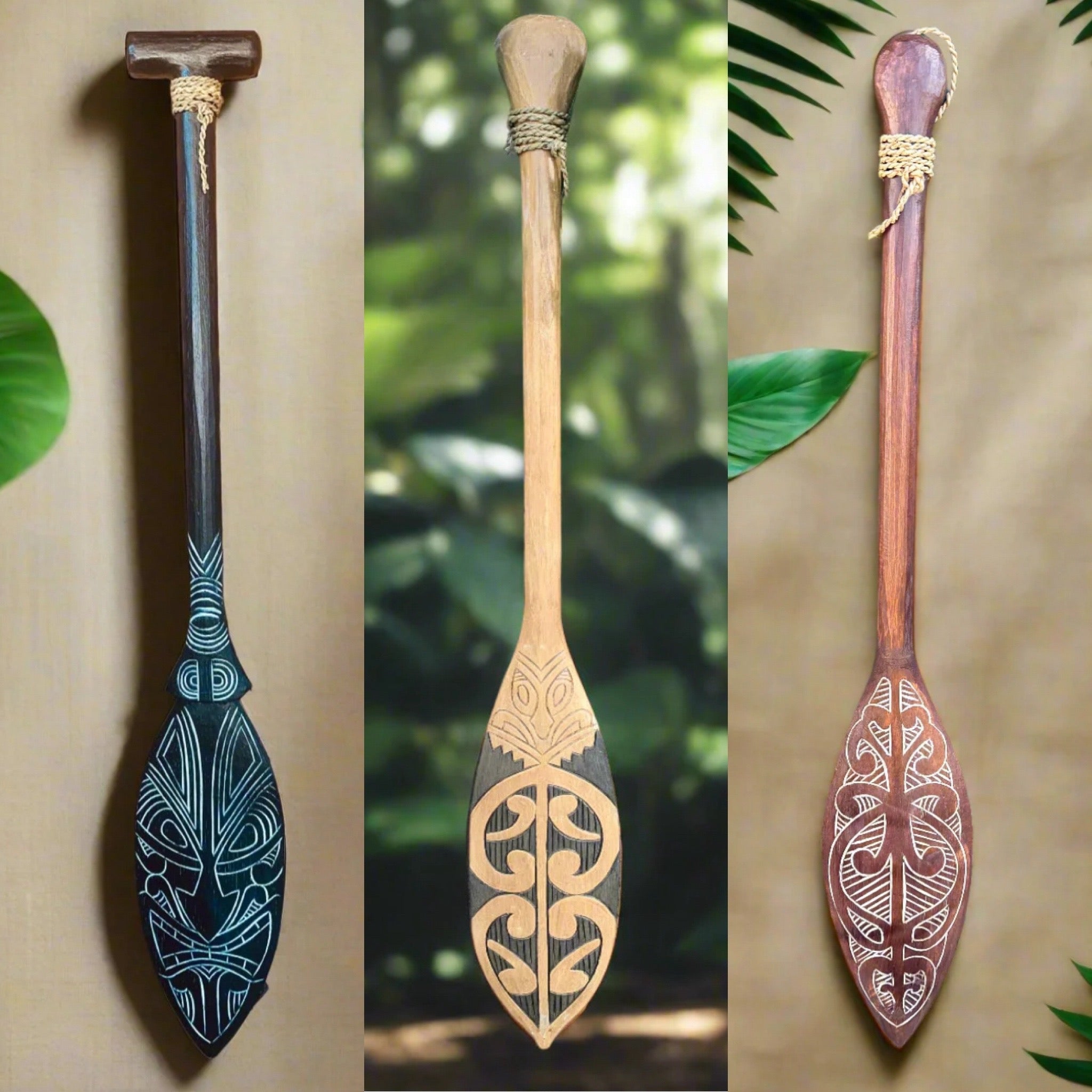 Three hand-carved wooden paddles with tiki-style patterns and rope-wrapped handles.