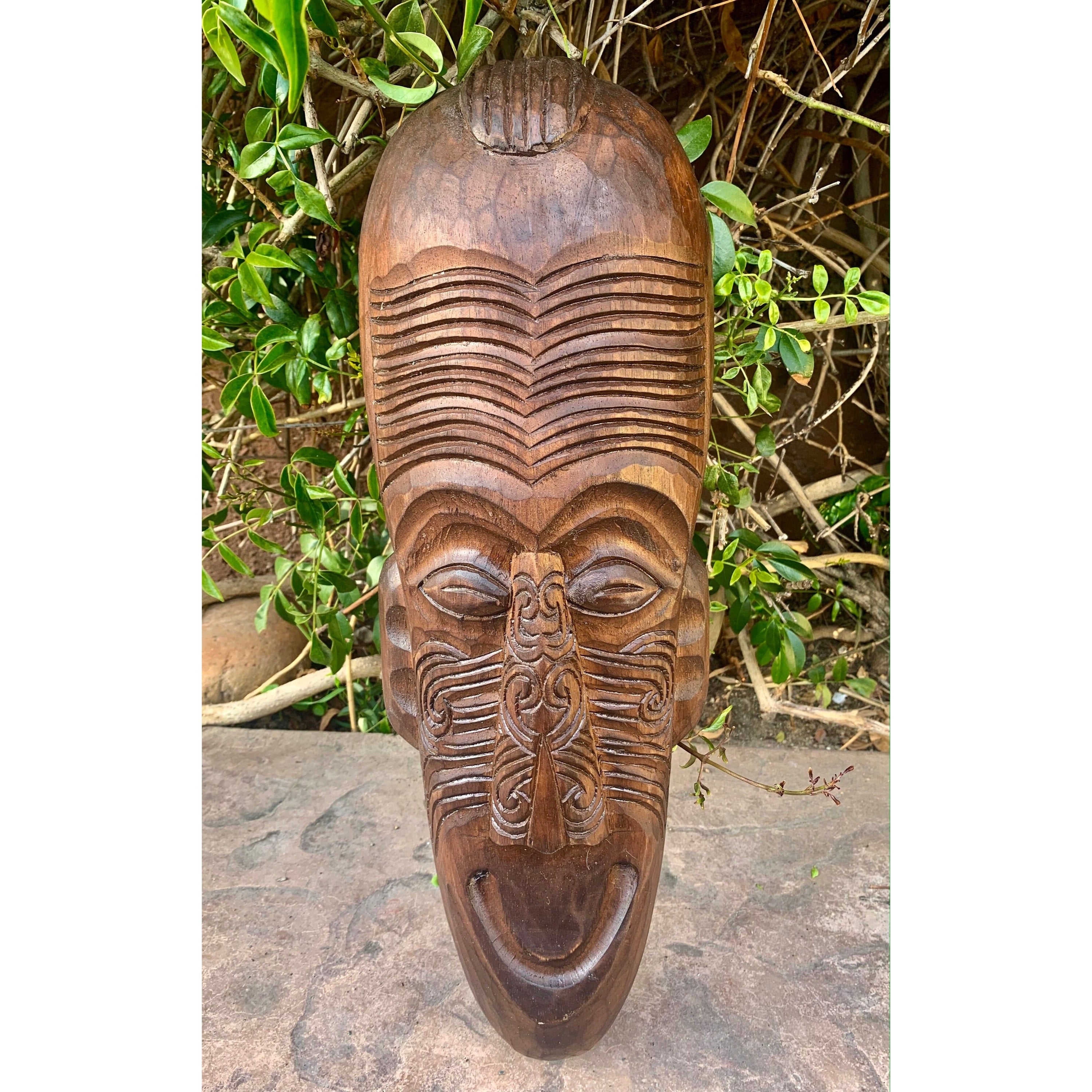 Hand-carved wooden tribal mask with grooved forehead and intricate facial patterns