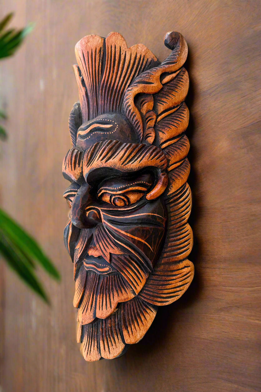 Hand-carved wooden tribal mask with intricate patterns mounted on a wooden wall