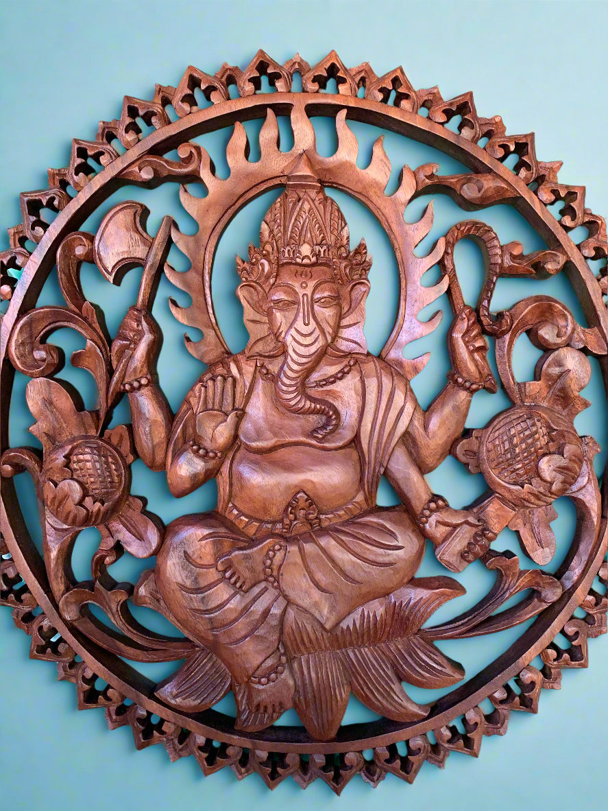 Intricately carved circular wooden Ganesha wall sculpture on teal background
